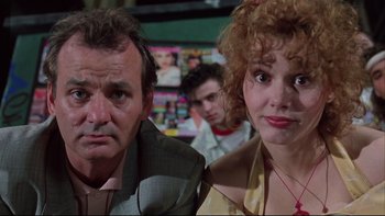 Movie still from “Quick Change” (1990), directed by Howard Franklin – A man and a woman sitting next to each other in a room; Close Up shot, Over the shoulder angle