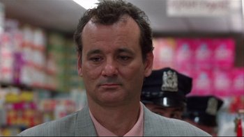 Movie still from “Quick Change” (1990), directed by Howard Franklin – A man in a gray suit and a pink shirt; Close Up shot, Low angle