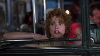 Movie still from “Quick Change” (1990), directed by Howard Franklin – A woman with curly red hair is looking out a window; Close Up shot, Over the shoulder angle