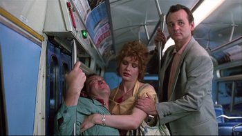 Movie still from “Quick Change” (1990), directed by Howard Franklin – A man and a woman on a bus with another man; Medium shot, Low angle