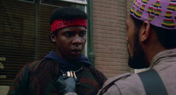 Movie still from “Quicksilver” (1986), directed by Thomas Michael Donnelly – A man wearing a red bandana talking to another man; Close Up shot, Over the shoulder angle