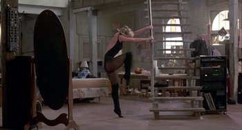 Movie still from “Quicksilver” (1986), directed by Thomas Michael Donnelly – A woman in black leotard doing a trick on a metal pole; Wide shot, Low angle