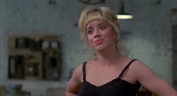Movie still from “Quicksilver” (1986), directed by Thomas Michael Donnelly – A woman with blonde hair wearing a black top; Close Up shot, Over the shoulder angle