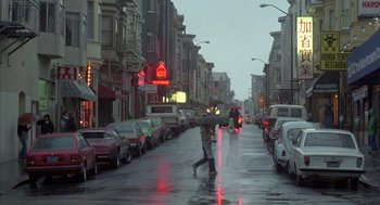 Movie still from “Quicksilver” (1986), directed by Thomas Michael Donnelly – Two people walking down the street with an umbrella; Wide shot, Low angle