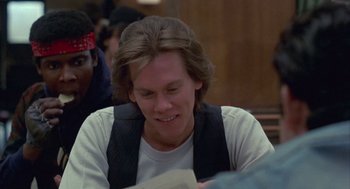 Movie still from “Quicksilver” (1986), directed by Thomas Michael Donnelly – A man sitting at a table reading a paper; Close Up shot, Over the shoulder angle