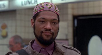 Movie still from “Quicksilver” (1986), directed by Thomas Michael Donnelly – A person with a beard wearing a hat; Close Up shot, Low angle