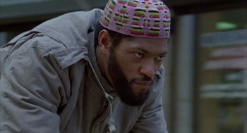 Movie still from “Quicksilver” (1986), directed by Thomas Michael Donnelly – A man with a colorful hat is looking at the camera; Close Up shot, Low angle