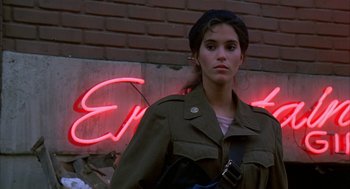 Movie still from “Quicksilver” (1986), directed by Thomas Michael Donnelly – A young woman in a military uniform standing in front of a neon sign; Close Up shot, Low angle