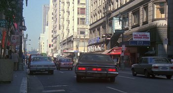 Movie still from “Quicksilver” (1986), directed by Thomas Michael Donnelly – Cars driving down a street in a city; Extreme Wide shot, High angle