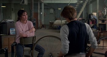 Movie still from “Quicksilver” (1986), directed by Thomas Michael Donnelly – Two people sitting in a room next to each other; Medium shot, Over the shoulder angle