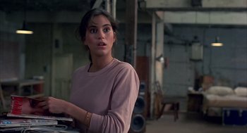 Movie still from “Quicksilver” (1986), directed by Thomas Michael Donnelly – A woman in a pink shirt is sitting at a table; Close Up shot, Over the shoulder angle
