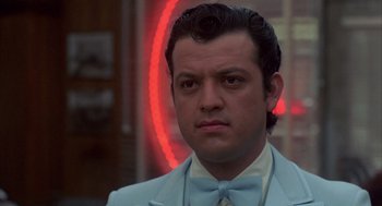 Movie still from “Quicksilver” (1986), directed by Thomas Michael Donnelly – A person wearing a suit and bow tie; Close Up shot, Low angle