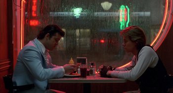 Movie still from “Quicksilver” (1986), directed by Thomas Michael Donnelly – A man and a woman sitting at a table in a restaurant; Medium shot, Low angle
