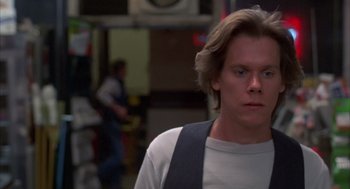Movie still from “Quicksilver” (1986), directed by Thomas Michael Donnelly – A man with long blonde hair wearing a white t - shirt; Close Up shot, Low angle