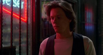 Movie still from “Quicksilver” (1986), directed by Thomas Michael Donnelly – A young man standing in front of a neon sign; Close Up shot, Low angle