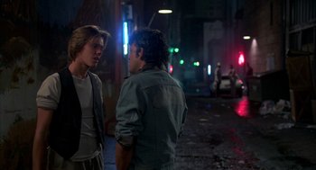 Movie still from “Quicksilver” (1986), directed by Thomas Michael Donnelly – Two young men standing on the side of the street; Medium shot, Over the shoulder angle