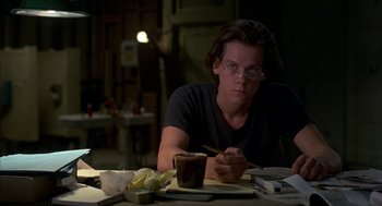 Movie still from “Quicksilver” (1986), directed by Thomas Michael Donnelly – A man sitting at a table with a cup of coffee; Medium shot, Low angle
