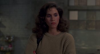 Movie still from “Quicksilver” (1986), directed by Thomas Michael Donnelly – A young woman with long curly brown hair wearing a sweater; Close Up shot, High angle