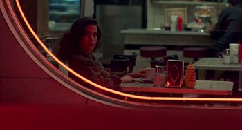 Movie still from “Quicksilver” (1986), directed by Thomas Michael Donnelly – A woman sitting at a table in front of a mirror; Medium shot, Over the shoulder angle