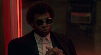 Movie still from “Quicksilver” (1986), directed by Thomas Michael Donnelly – A man in a suit and sunglasses is pointing; Close Up shot, Low angle