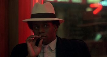 Movie still from “Quicksilver” (1986), directed by Thomas Michael Donnelly – A man wearing a white hat and smoking a cigarette; Close Up shot, Low angle