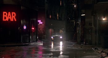 Movie still from “Quicksilver” (1986), directed by Thomas Michael Donnelly – A car driving down a street at night; Wide shot, High angle