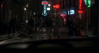 Movie still from “Quicksilver” (1986), directed by Thomas Michael Donnelly – A group of people walking down a street at night; Wide shot, High angle