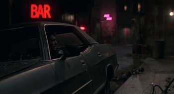 Movie still from “Quicksilver” (1986), directed by Thomas Michael Donnelly – A man sitting in the driver's seat of a parked car; Wide shot, Over the shoulder angle