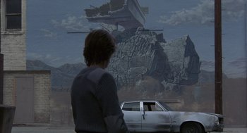 Movie still from “Quicksilver” (1986), directed by Thomas Michael Donnelly – A man standing in front of a car in front of a painting; Wide shot, Low angle