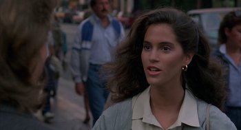 Movie still from “Quicksilver” (1986), directed by Thomas Michael Donnelly – A woman with long brown hair walking down a street; Close Up shot, Over the shoulder angle
