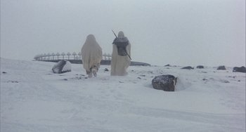 Movie still from “Quintet” (1979), directed by Robert Altman – A couple of people standing on top of a snow covered slope; Extreme Wide shot, Low angle
