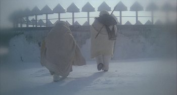 Movie still from “Quintet” (1979), directed by Robert Altman – A couple of people walking through the snow; Wide shot, Low angle