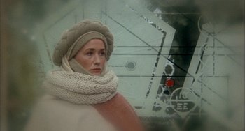 Movie still from “Quintet” (1979), directed by Robert Altman – A woman wearing a hat and scarf standing next to a traffic light; Close Up shot, Low angle