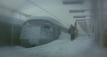 Movie still from “Quintet” (1979), directed by Robert Altman – A man is walking through the snow near a train; Wide shot, High angle