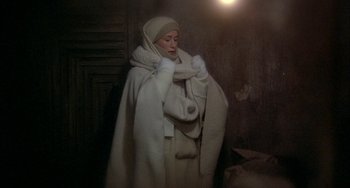 Movie still from “Quintet” (1979), directed by Robert Altman – A woman wearing a white coat and a white scarf; Medium shot, Low angle