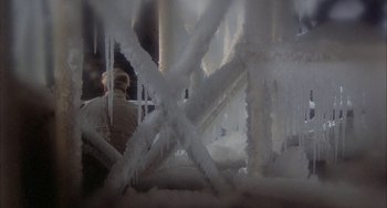 Movie still from “Quintet” (1979), directed by Robert Altman – A person standing in front of a building covered in ice; Wide shot, High angle