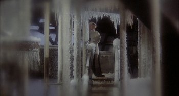 Movie still from “Quintet” (1979), directed by Robert Altman – A man standing in front of a building covered in icicles; Wide shot, Low angle