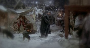 Movie still from “Quintet” (1979), directed by Robert Altman – A man in a fur coat standing next to a dog; Wide shot, High angle