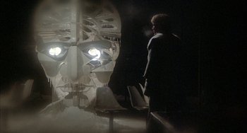 Movie still from “Quintet” (1979), directed by Robert Altman – A man standing in front of a wall with lights on it; Medium shot, Low angle