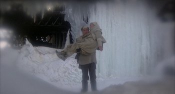 Movie still from “Quintet” (1979), directed by Robert Altman – A man carrying a child in a sling in the snow; Wide shot, High angle