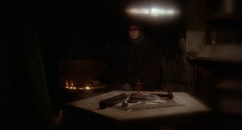 Movie still from “Quintet” (1979), directed by Robert Altman – A woman standing in front of a fireplace in the dark; Medium shot, High angle