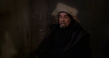 Movie still from “Quintet” (1979), directed by Robert Altman – A man with a beard wearing a hat and a black robe; Medium shot, Over the shoulder angle