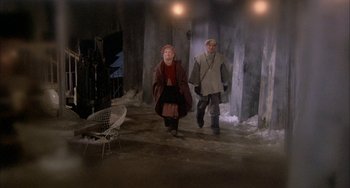Movie still from “Quintet” (1979), directed by Robert Altman – A man and a woman are walking in a dark room; Wide shot, High angle