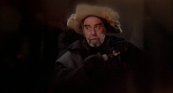 Movie still from “Quintet” (1979), directed by Robert Altman – An older man wearing a hat and holding a pipe; Medium shot, Over the shoulder angle