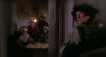 Movie still from “Quintet” (1979), directed by Robert Altman – A group of people sitting around a table; Medium shot, Over the shoulder angle