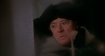 Movie still from “Quintet” (1979), directed by Robert Altman – An older man wearing a black hat looking out of a window; Close Up shot, Low angle