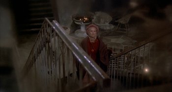 Movie still from “Quintet” (1979), directed by Robert Altman – A woman standing on the stairs of a house; Wide shot, High angle