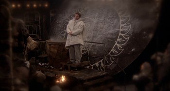 Movie still from “Quintet” (1979), directed by Robert Altman – A man standing in front of a wall with a fire; Wide shot, High angle