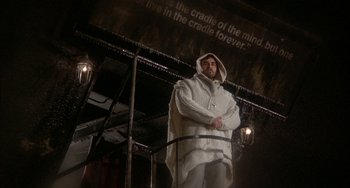 Movie still from “Quintet” (1979), directed by Robert Altman – A man in a white coat standing in front of a building; Medium shot, Low angle