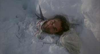 Movie still from “Quintet” (1979), directed by Robert Altman – A man with a beard is buried in the snow; Medium shot, Overhead angle